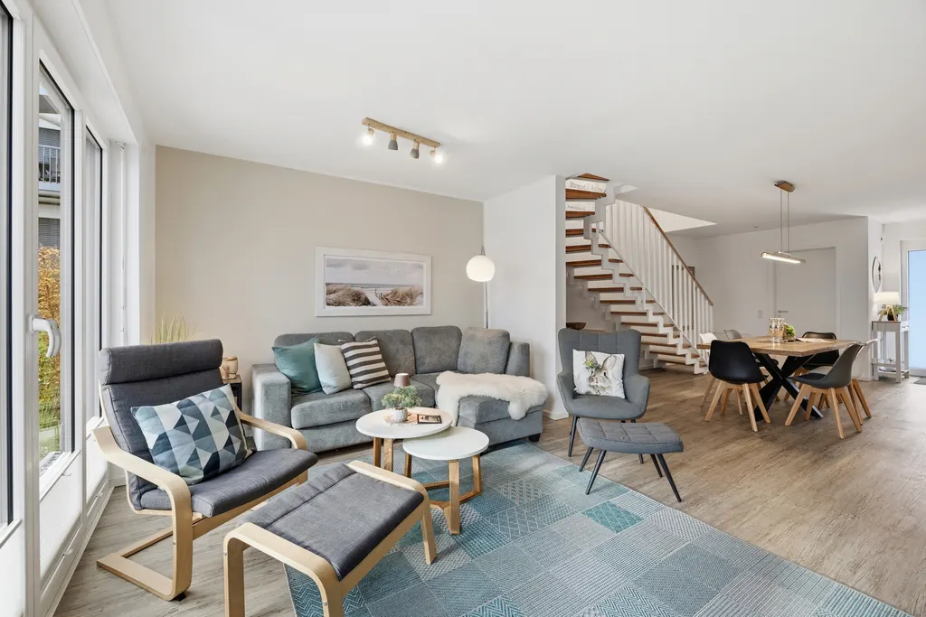 Wohnbereich mit Sofa, Sesseln und Treppe ins Obergeschoss